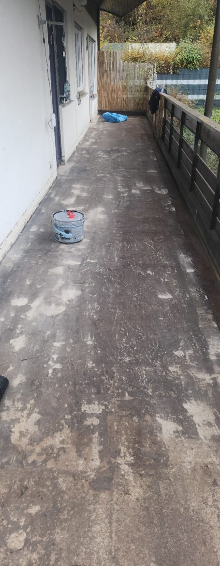 Leere Terrasse mit Holzgeländer und sichtbarem, unbefestigtem Boden.